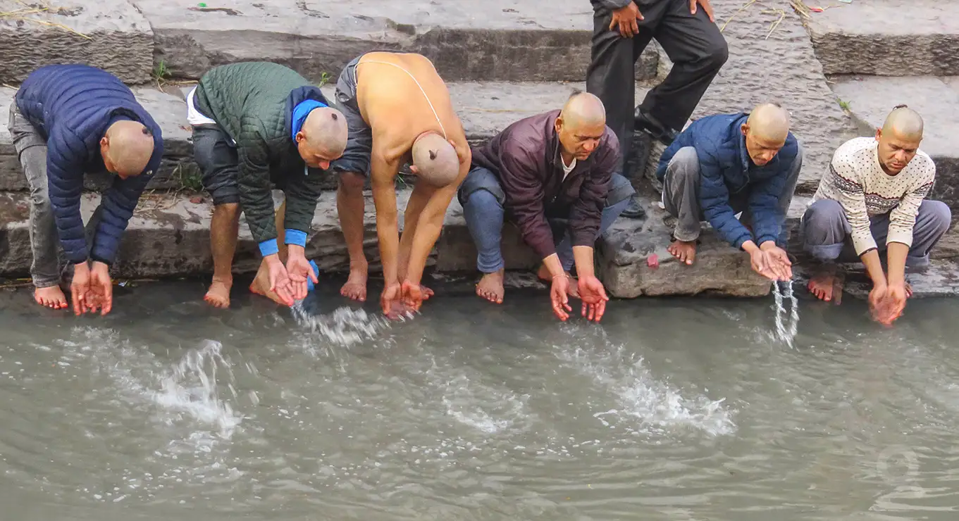 Cuando la pira ha dejado de arder, familiares proceden a nuevas abluciones y entierran restos de ceniza en el álveo del Bagmati.