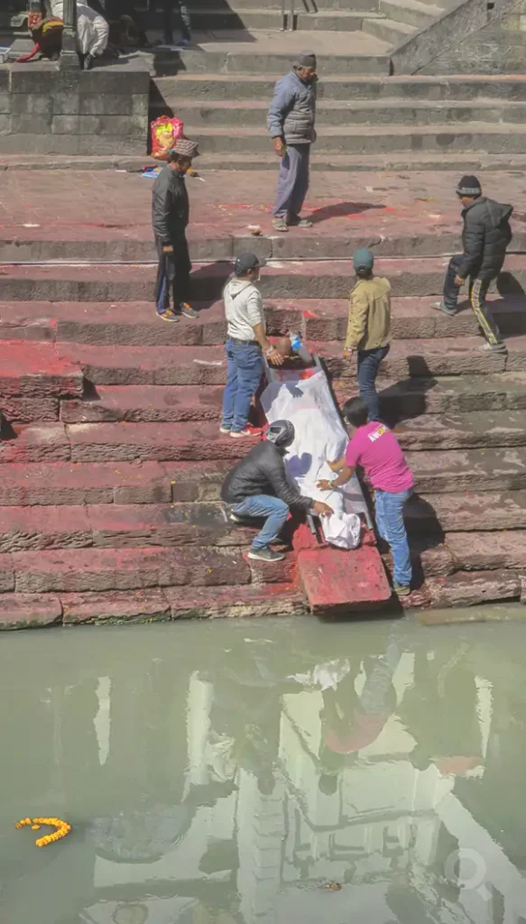 Escalinata del templo de Pasupatiná al momento de purificar el cadáver sobre el brahmanal en el Bagmati.