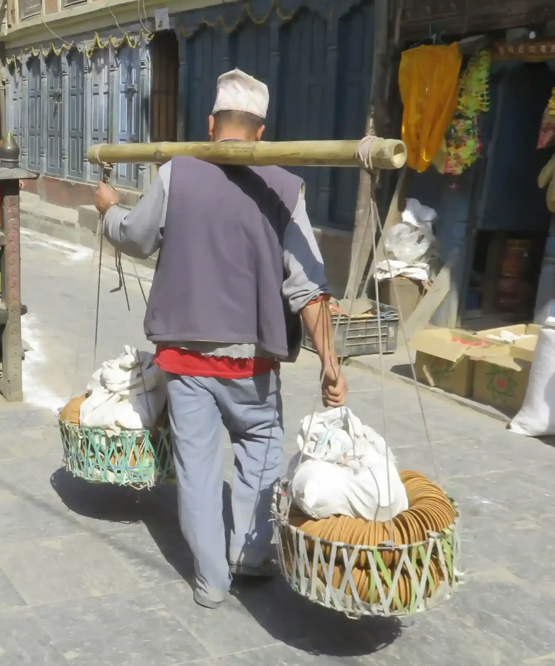El acarreador de comestibles en su balanza de bambú por las calles de Katmandú.